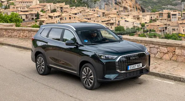Ebro S800 PHEV, un SUV moderno, aparcado en una carretera con un pueblo pintoresco de fondo.