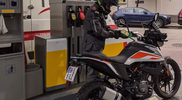 Motociclista repostando su moto 390 Adventure. La pregunta sobre qué gasolina usan las motos de 49cc es relevante para este tipo de vehículos.