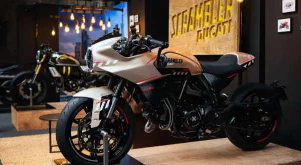 Una moto tipo scrambler color crema con detalles rojos y negros, lista para la aventura.
