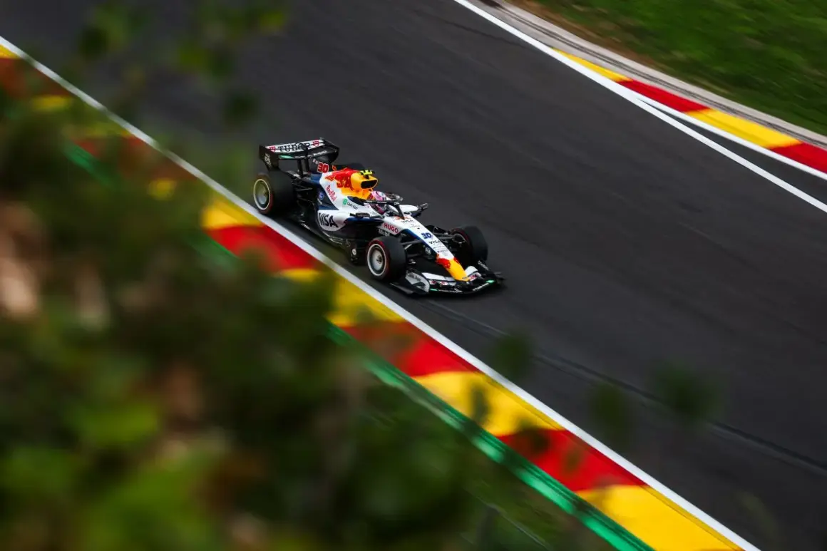 Liam Lawson compite en un coche de Fórmula 1 con los colores de Red Bull, acelerando en una curva con las marcas rojas y amarillas de la pista.