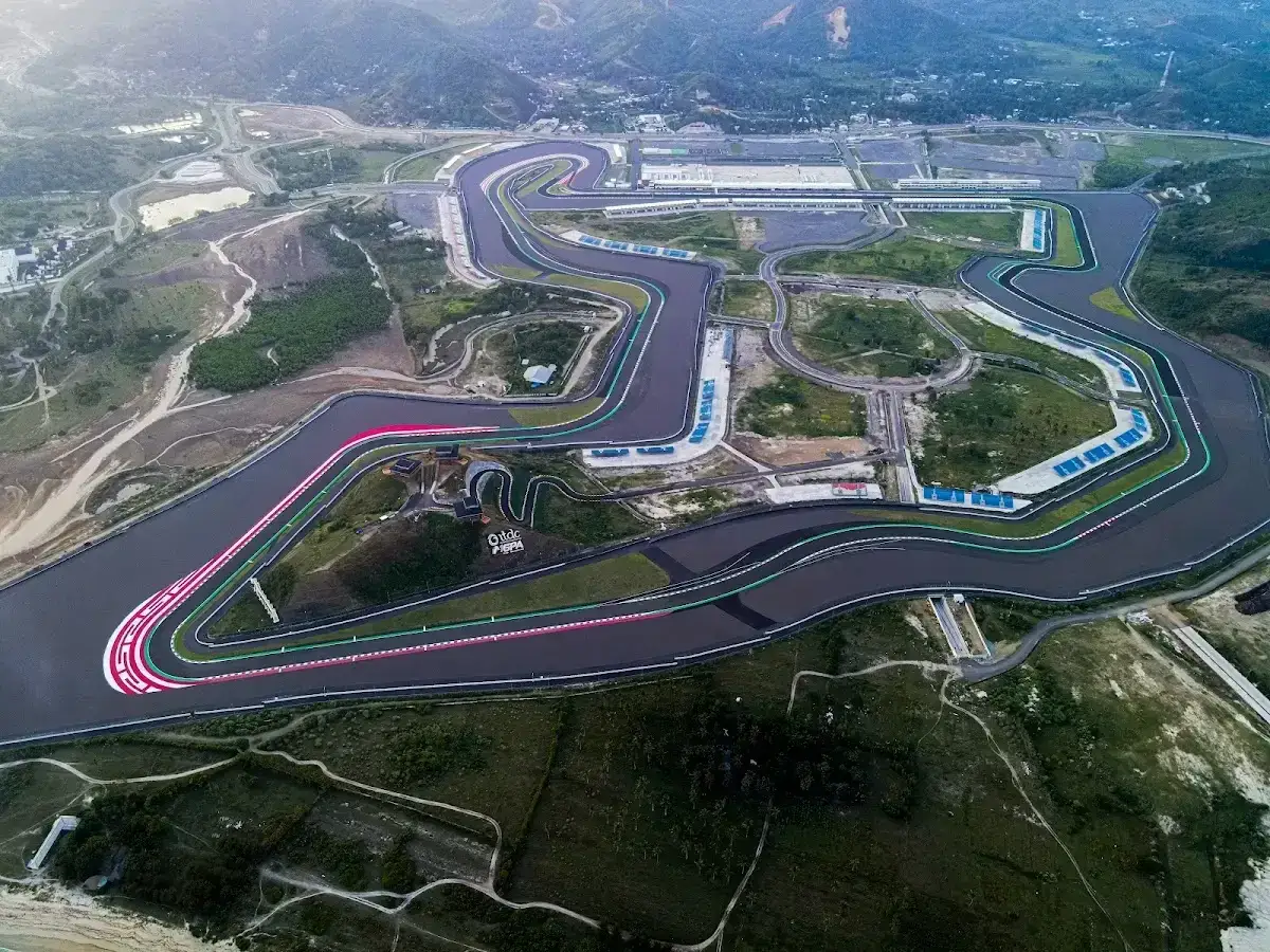 Vista aérea del Mandalika Circuit, una pista de carreras serpenteante rodeada de colinas verdes y el mar.