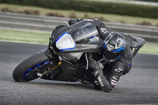 Piloto en Yamaha R1, la moto más potente, inclinado en una curva en circuito.