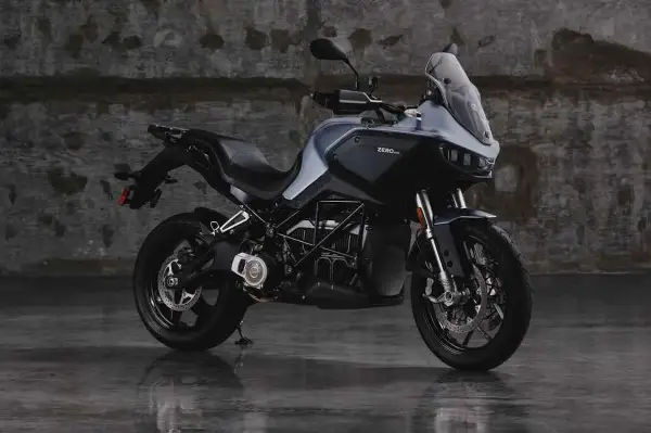 Motocicleta eléctrica Zero DSR/X, con potencia de 35kW, color gris oscuro, sobre suelo mojado y fondo de pared de ladrillo.
