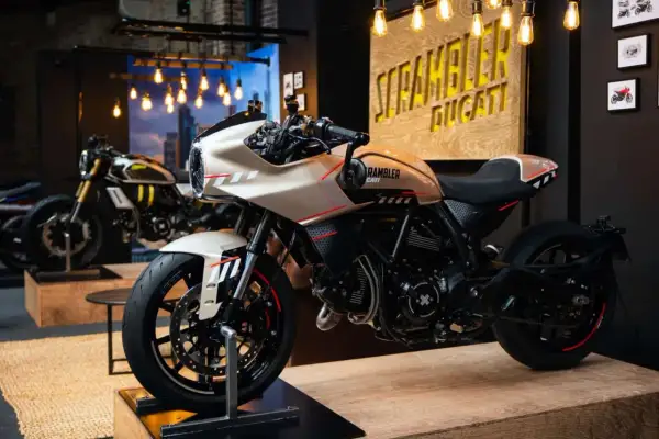 Una moto tipo scrambler color crema con detalles rojos y negros, lista para la aventura.