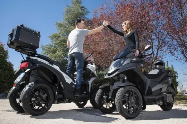 Pareja chocando las manos junto a sus Qooder QV3, listos para una aventura.